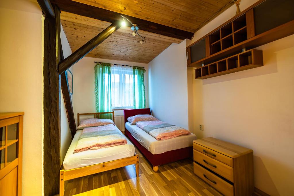 two beds in a room with wooden floors and a window at Dum Slunicko in Klobouky u Brna