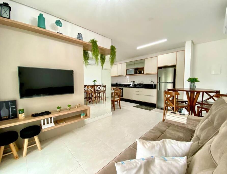 sala de estar con sofá y TV y cocina en Apto 80m da Praia Grande vista mar!, en Governador Celso Ramos