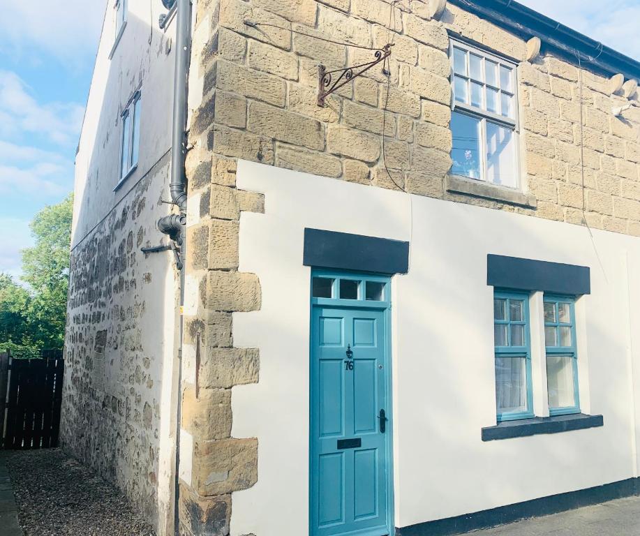 a building with a blue door and two windows at Inviting townhouse in Bedlington in Bedlington