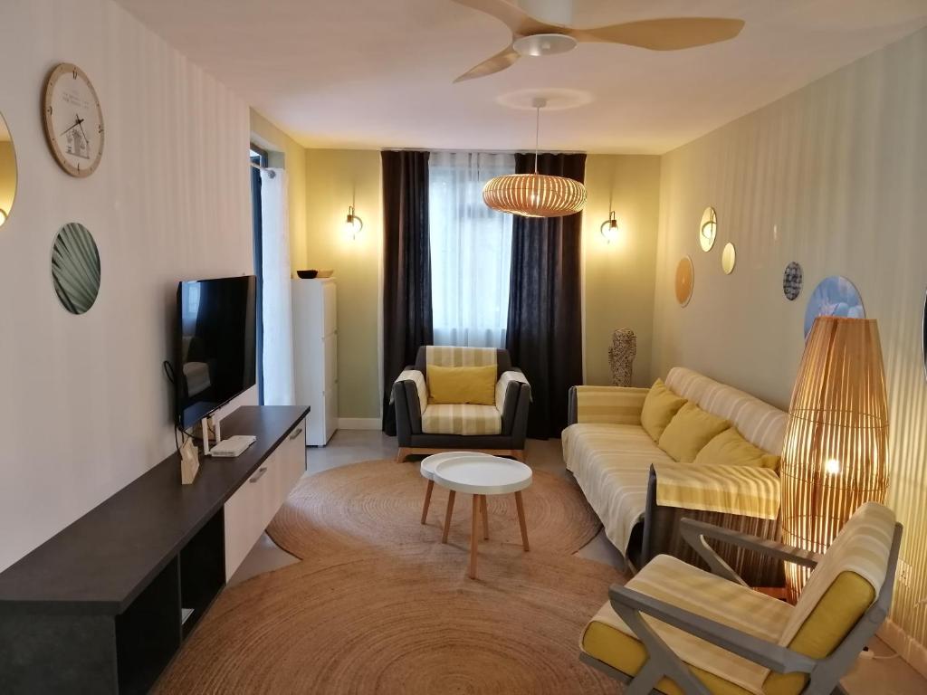 ein Wohnzimmer mit einem Sofa und einem TV in der Unterkunft Les Cerisiers-Beach Apartment with Pool, Centrally Located in Flic-en-Flac in Flic-en-Flac