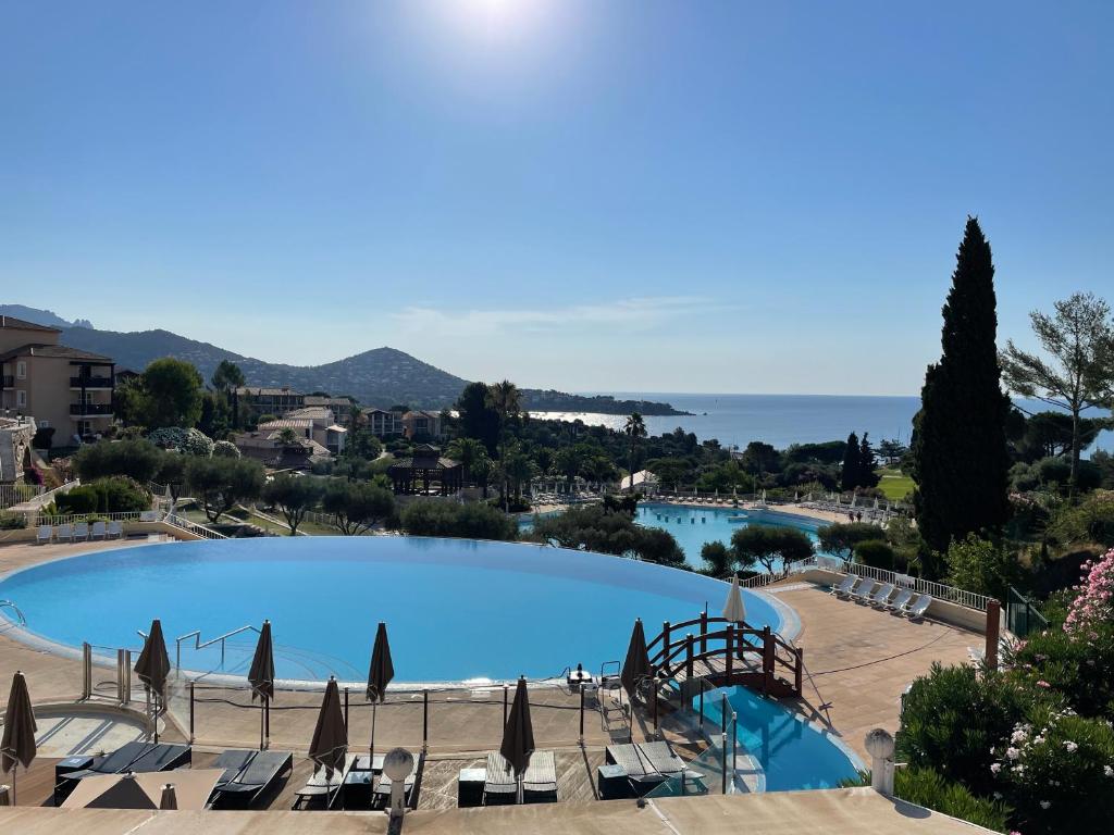 ein großer Pool mit Stühlen und Sonnenschirmen in der Unterkunft Cap Estérel Rivièra Studio in Saint-Raphaël