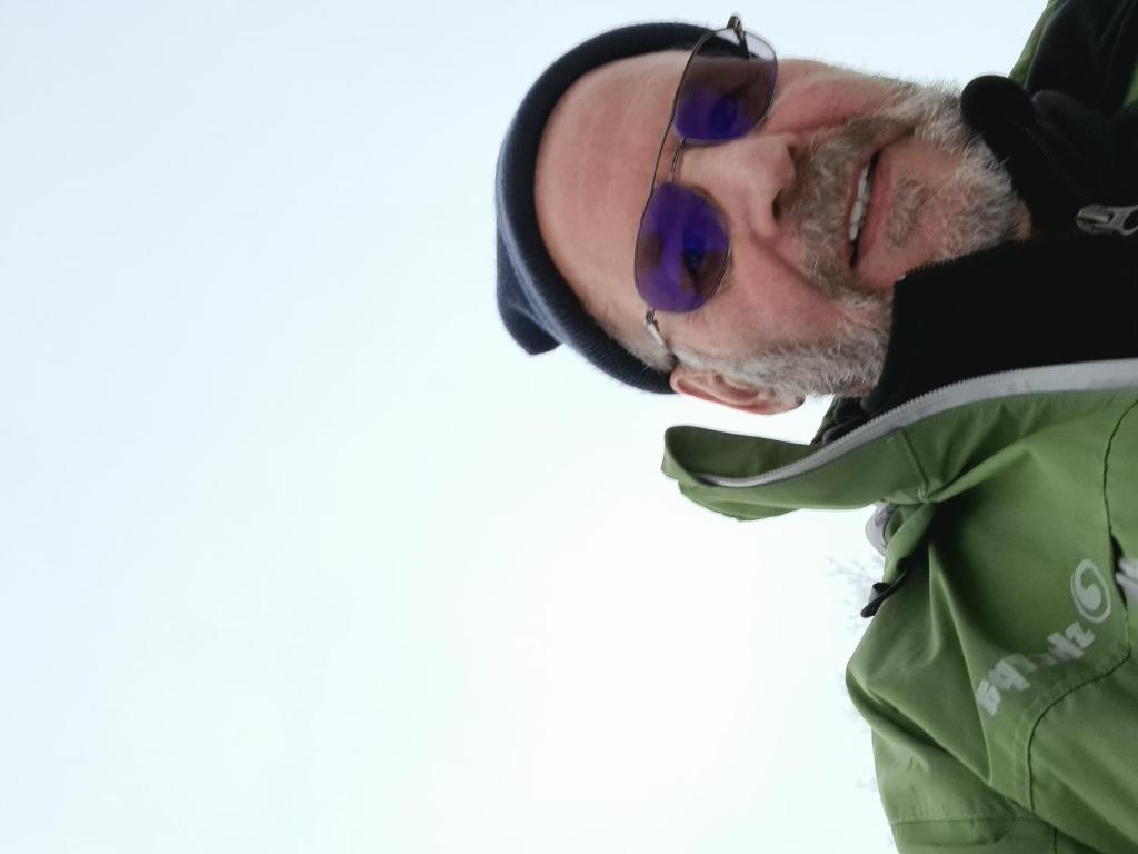 un homme portant des lunettes de soleil et une veste verte dans l'établissement Lumpaz, à Santa Maria Val Müstair