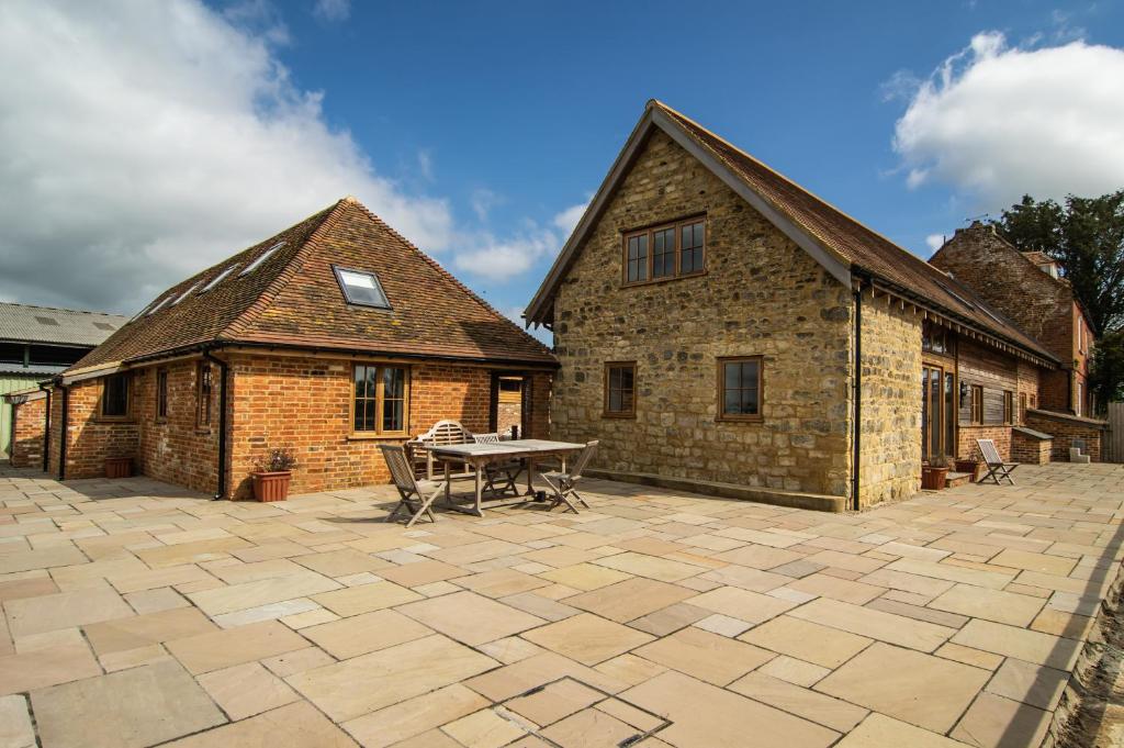 a stone patio with a table and a building at Parkfields Barns Self Catering Accommodation in Buckingham