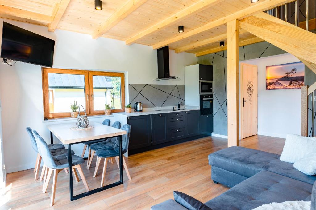 a kitchen and living room with a table and a couch at Domki Pod Lasem in Krościenko