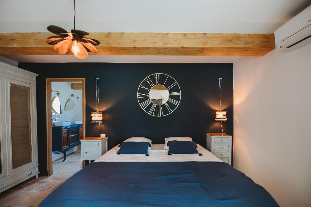 a bedroom with a large bed and a clock on the wall at Mas des Ecoliers in Châteaurenard