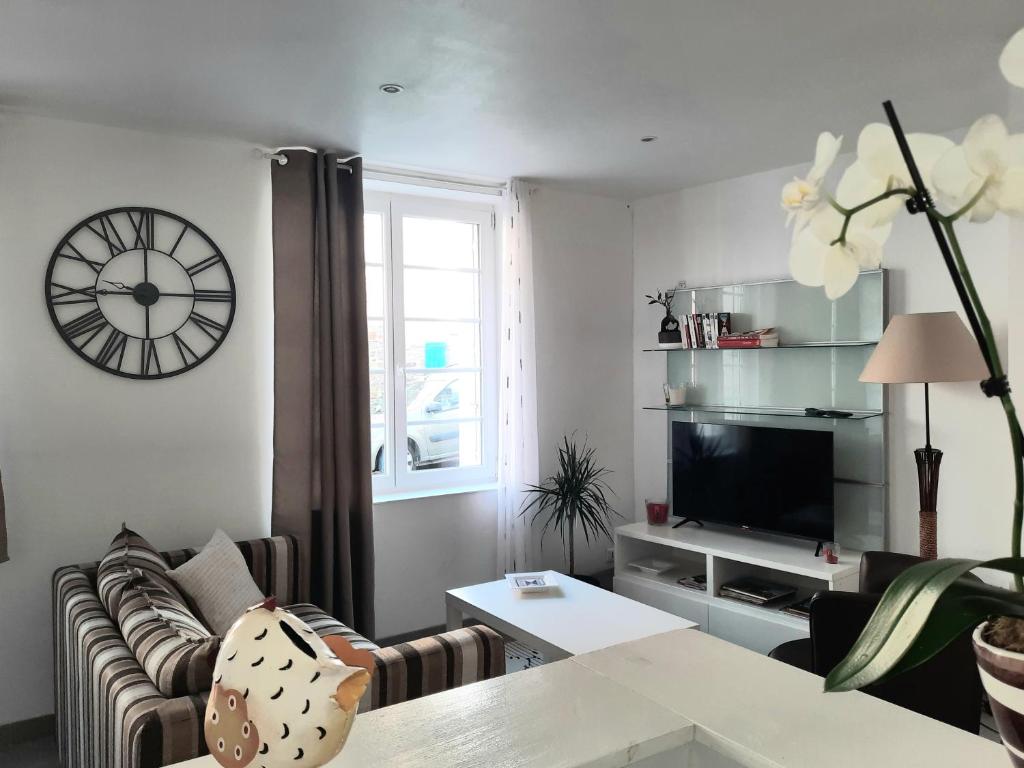 un salon avec un canapé et une horloge au mur dans l'établissement Appartement centre ville rue calme 2 pièces classé 3 étoiles, à Lannion