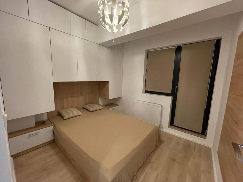 um pequeno quarto com uma cama e um lustre em Riverside Luxury Apartment Near President Palace em Bucareste