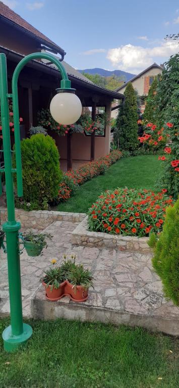 a garden with flowers and a green pole and a building at Apartman Samardžić in Višegrad
