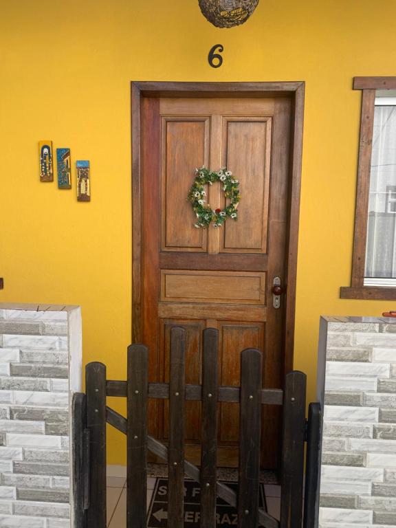 una puerta de madera con una corona en una pared amarilla en Casa beira mar Jacaraipe. en Serra