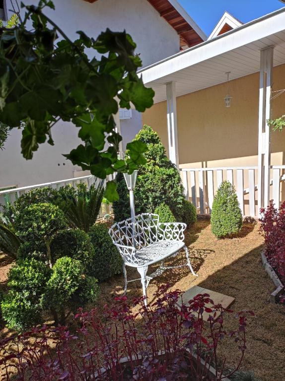 a white bench sitting in the middle of a garden at Pousada Serrano in Campos do Jordão