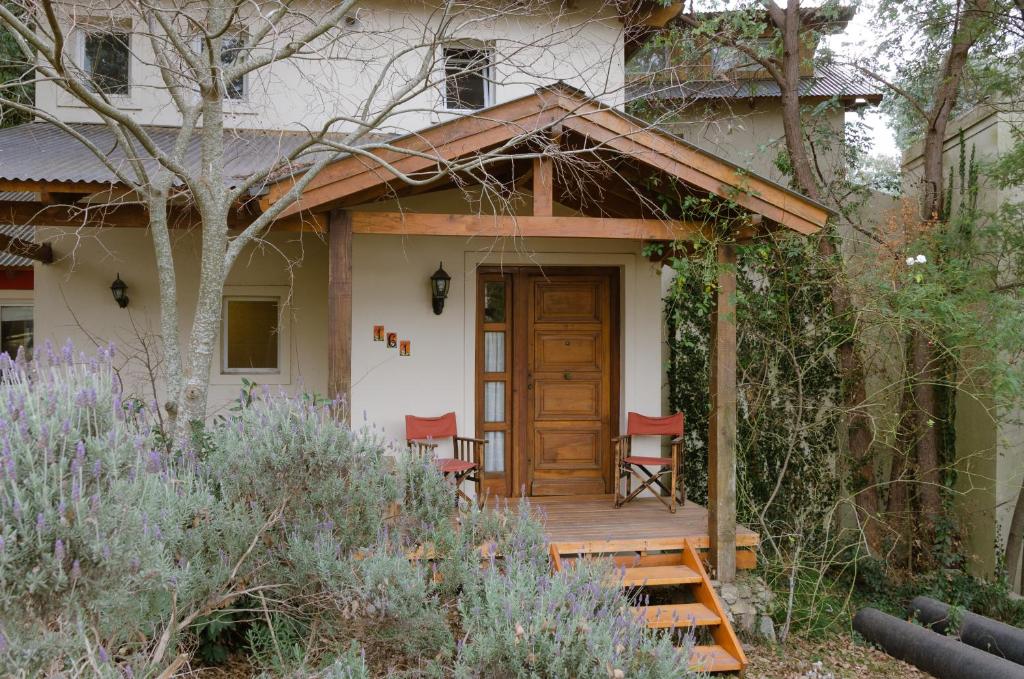 een huis met een houten deur en twee stoelen op een veranda bij Entre Sierras B&B in Tandil