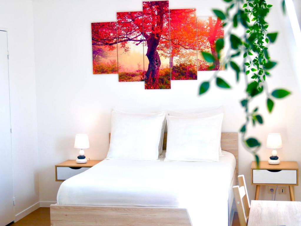 - une chambre avec un lit blanc et des peintures d'arbres rouges sur le mur dans l'établissement Le Petit Soleil de Corbeil, à Corbeil-Essonnes