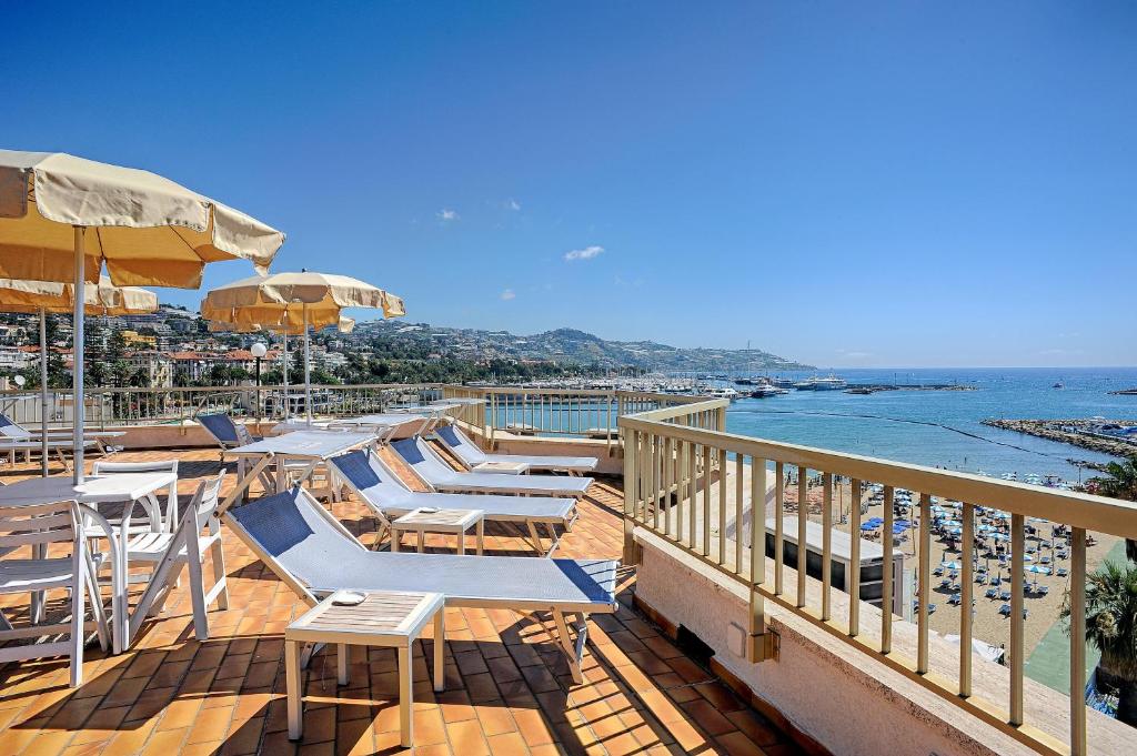 - une terrasse avec des chaises longues et des parasols ainsi qu'une plage dans l'établissement Residence Dei Due Porti, à Sanremo