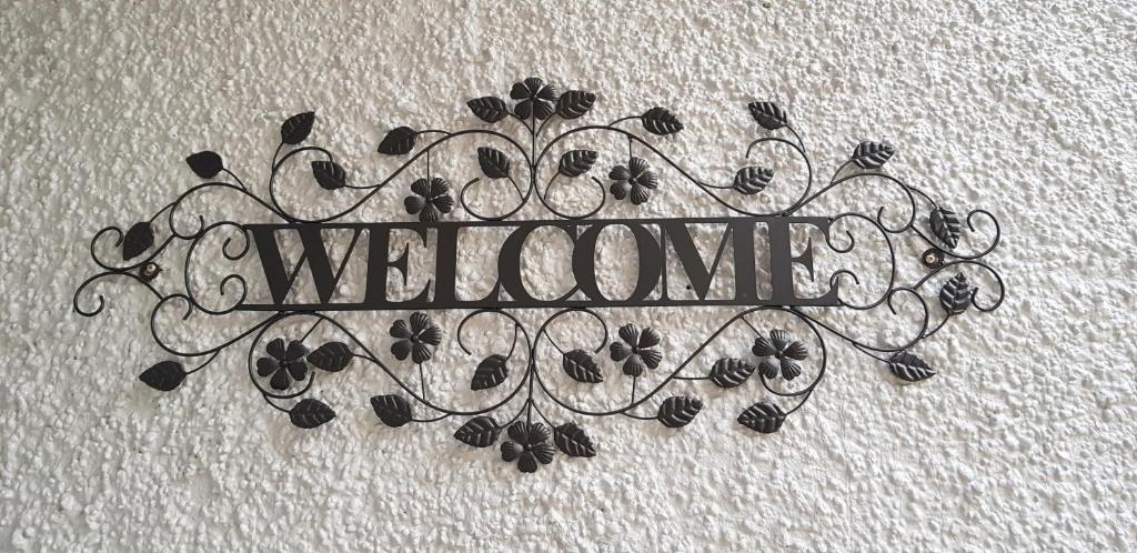 a metal sign with the word welcome on a wall at Pioneer Motel in Palmerston