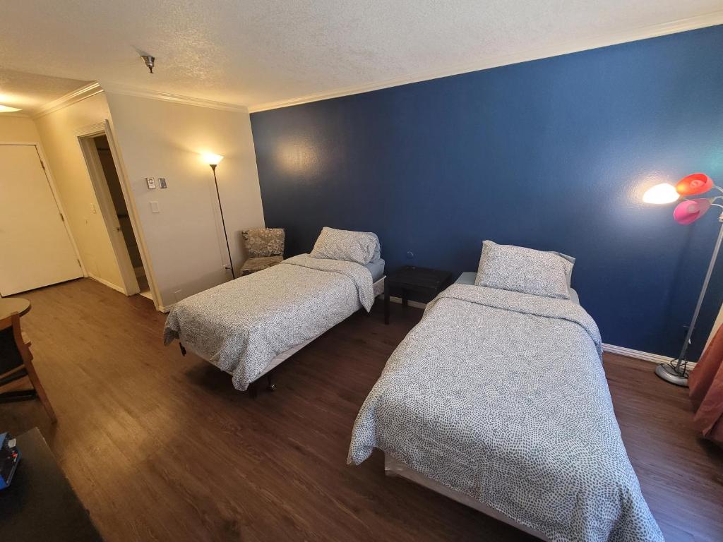 a room with two beds and a blue wall at (A11) Lovely Double Bed Unit in Los Angeles