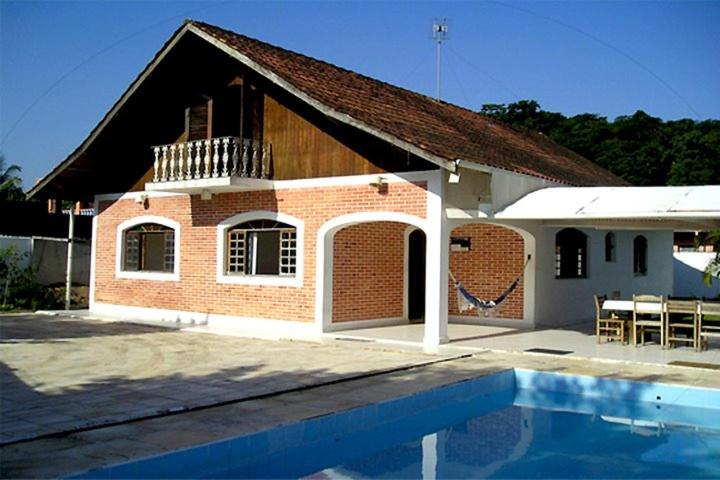 a brick house with a swimming pool in front of it at Pousada Pérola do Guarujá Ltda- Me in Guarujá