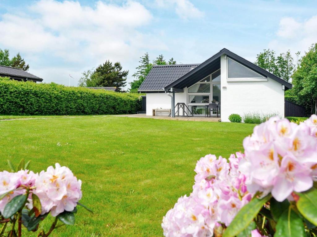 a white house with pink flowers in the yard at 6 person holiday home in Struer in Remmer Strand