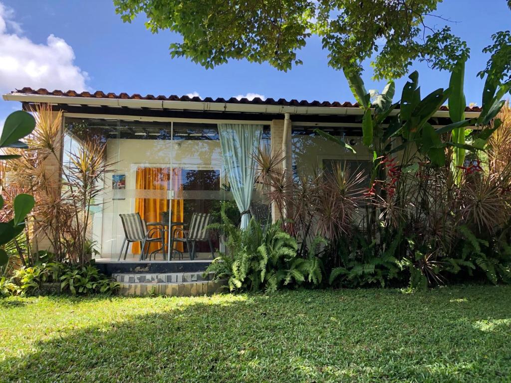 a house with chairs and plants in the yard at CASA BOUTIQUE MARACA Privativa in Porto De Galinhas