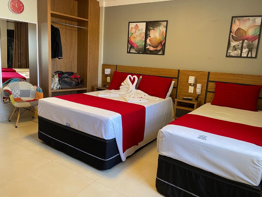 Un dormitorio con dos camas con sábanas rojas y blancas. en Araras Apart Service I, en Caldas Novas