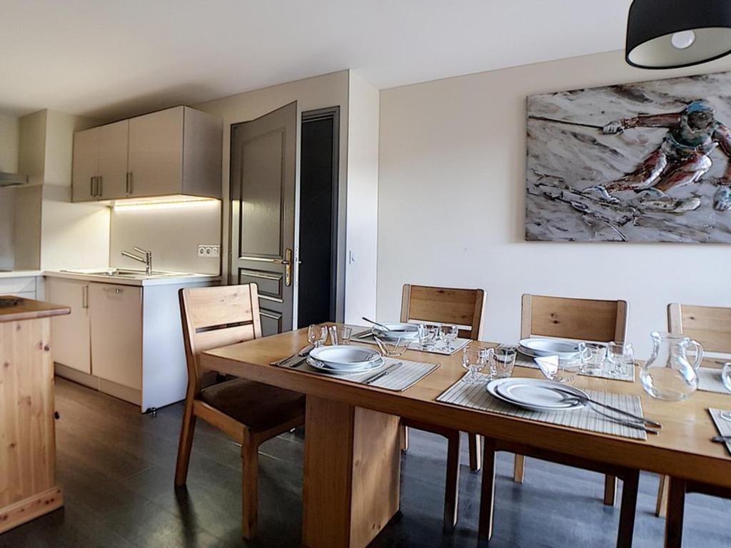 a kitchen and dining room with a wooden table and chairs at Appartement de standing rénové aux Belleville avec balcon, accès pistes, WiFi, sauna et hammam - FR-1-344-808 in Levassaix
