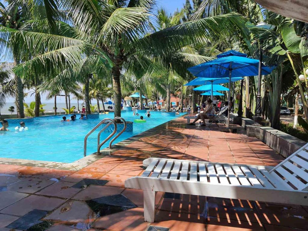 a swimming pool with people in a resort with palm trees at Eureka Resort, Hai Tien Beach in Thanh Hóa