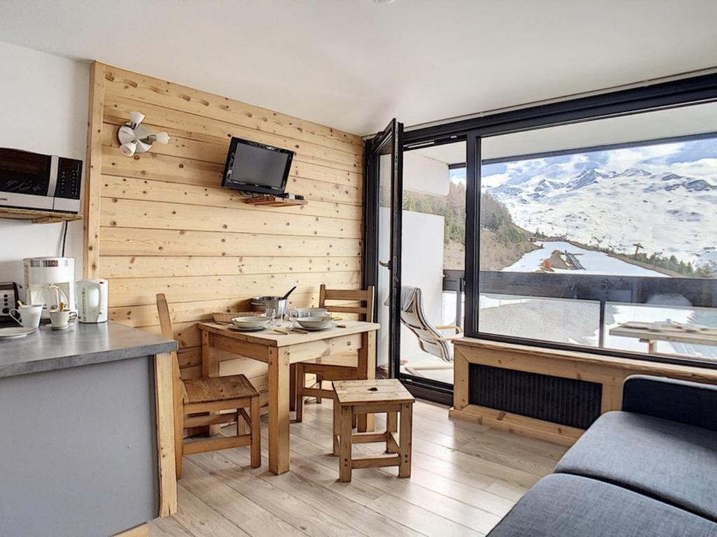 un salon avec une table et une grande fenêtre dans l'établissement Studio rénové au centre avec balcon - FR-1-344-926, aux Menuires