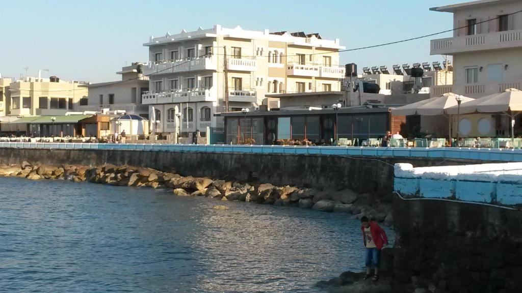 una persona in piedi accanto a un corpo idrico con edifici di Mandy Suites a Kíssamos