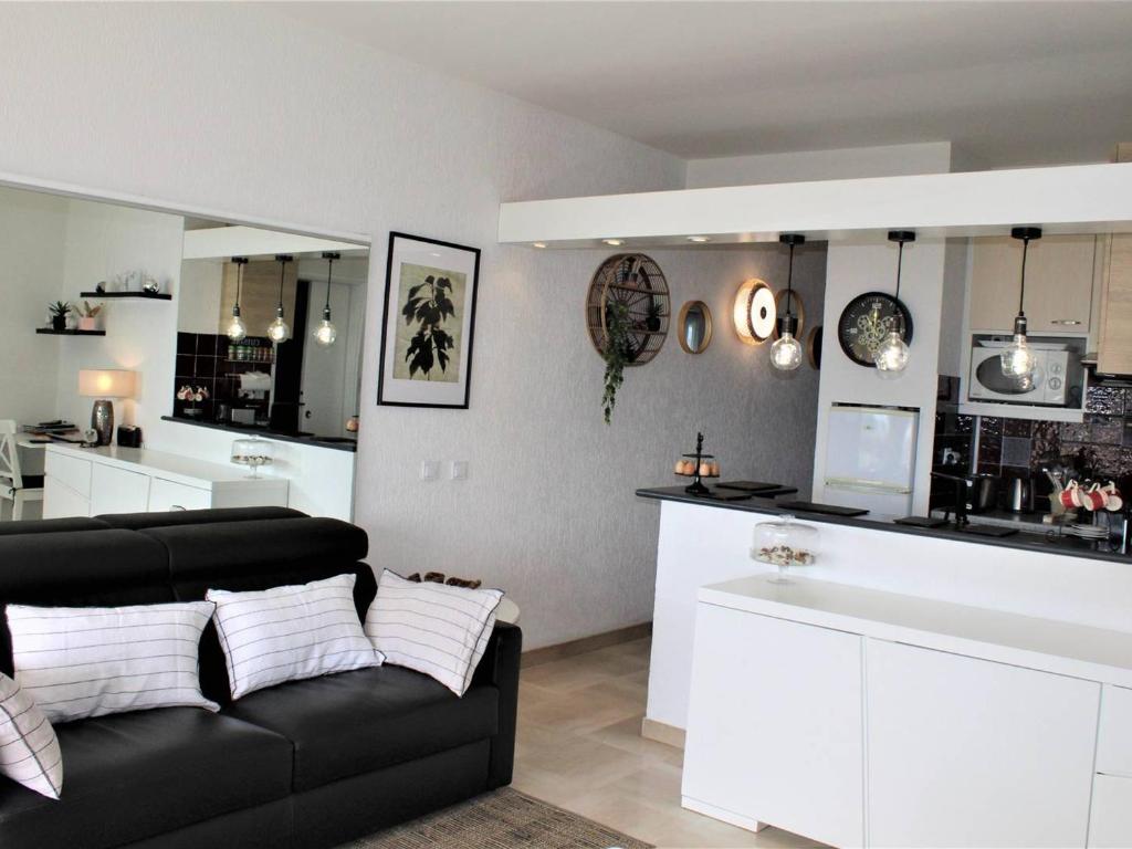 un salon avec un canapé noir et une cuisine dans l'établissement Appartement Contemporain, 4 Couchages, Climatisé avec Parking - FR-1-252A-82, à Villeneuve-Loubet