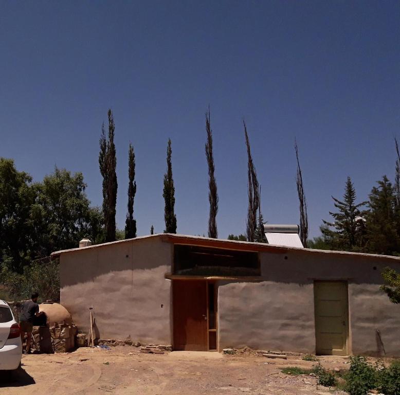 a small building with a group of cypress trees behind it at Posada Huacalera (Tropico de Capricornio) in Huacalera