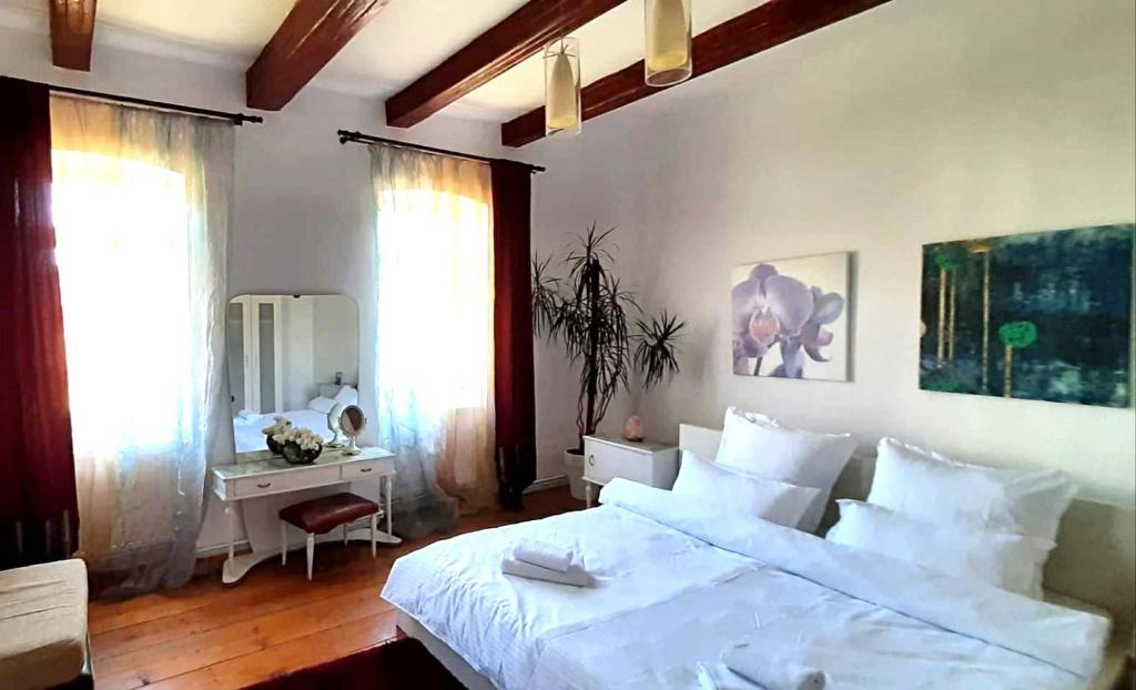 1 dormitorio con 1 cama blanca grande y escritorio en Casa din colțul Cetății en Hărman