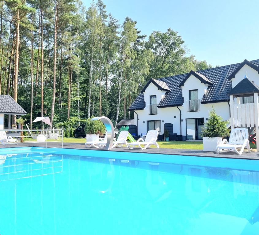 a house with a swimming pool in front of a house at Nadmorska Przystan - Apartamenty caloroczne in Ustka