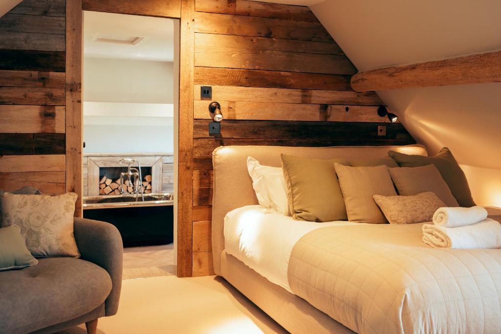 um quarto com uma cama e uma cadeira em Brook Cottage em Burford