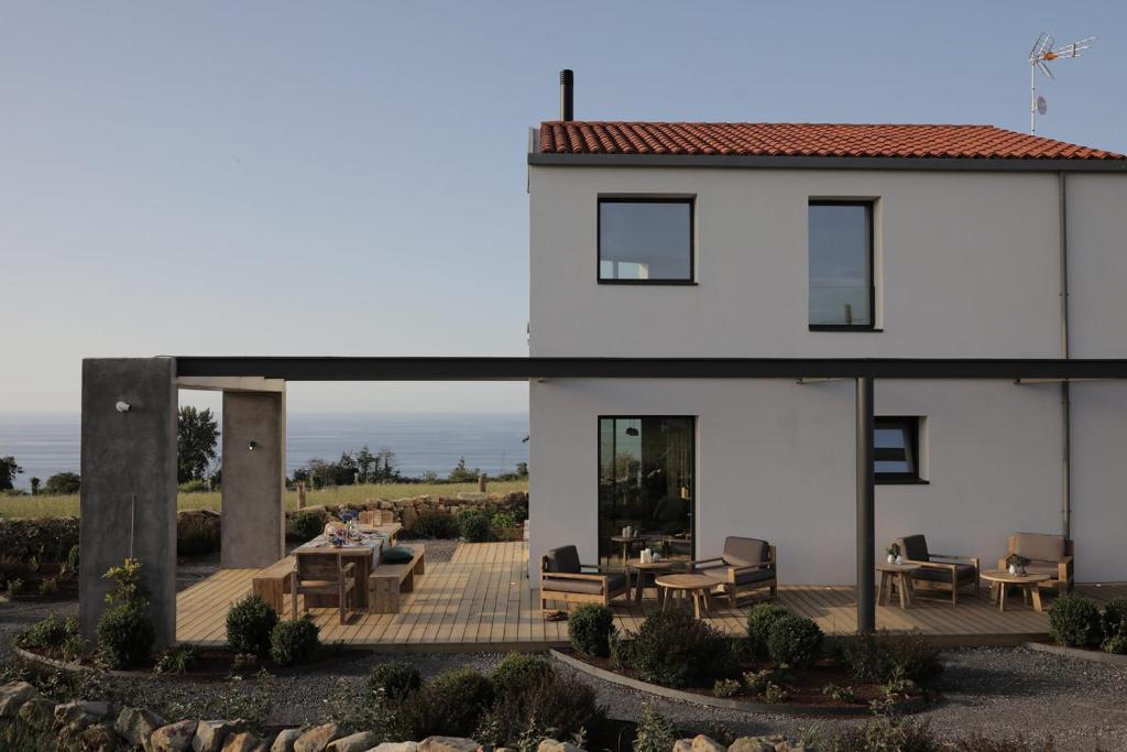 een wit huis met een patio met tafels en stoelen bij El Faro Unkempt - Tazones in Villar