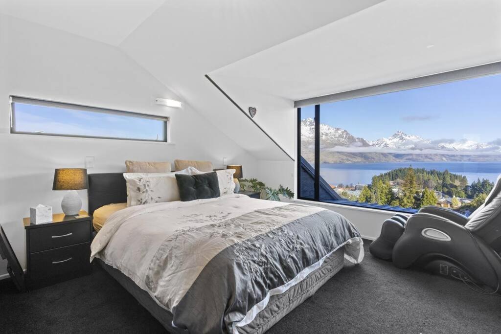 a bedroom with a large window with a bed and a chair at Awesome Studio - Amazing Mountain & Lake Views in Queenstown
