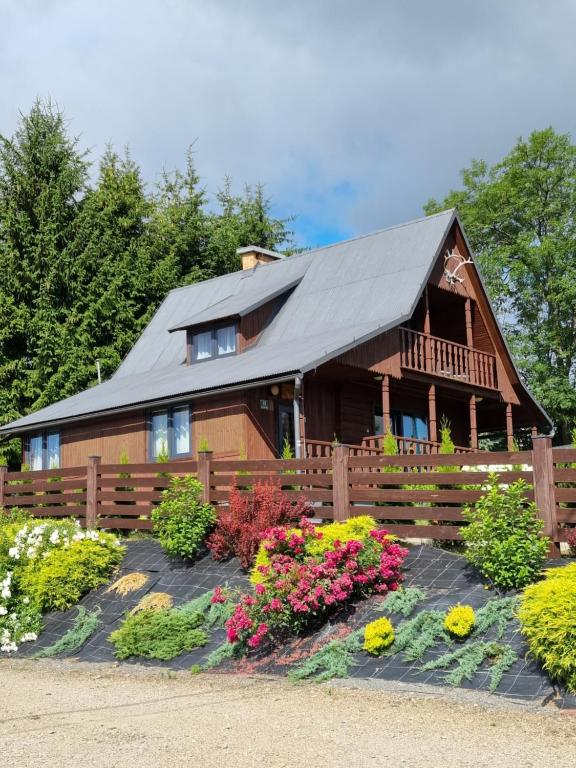 a house with a fence and flowers in front of it at Domek Anna Zawóz in Zawóz