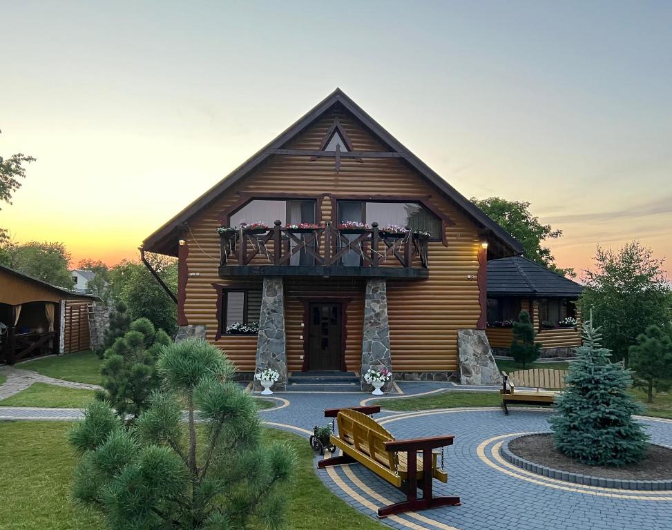 Cabaña de madera con balcón y banco en Rodynne Gnizdo, en Pochaiv