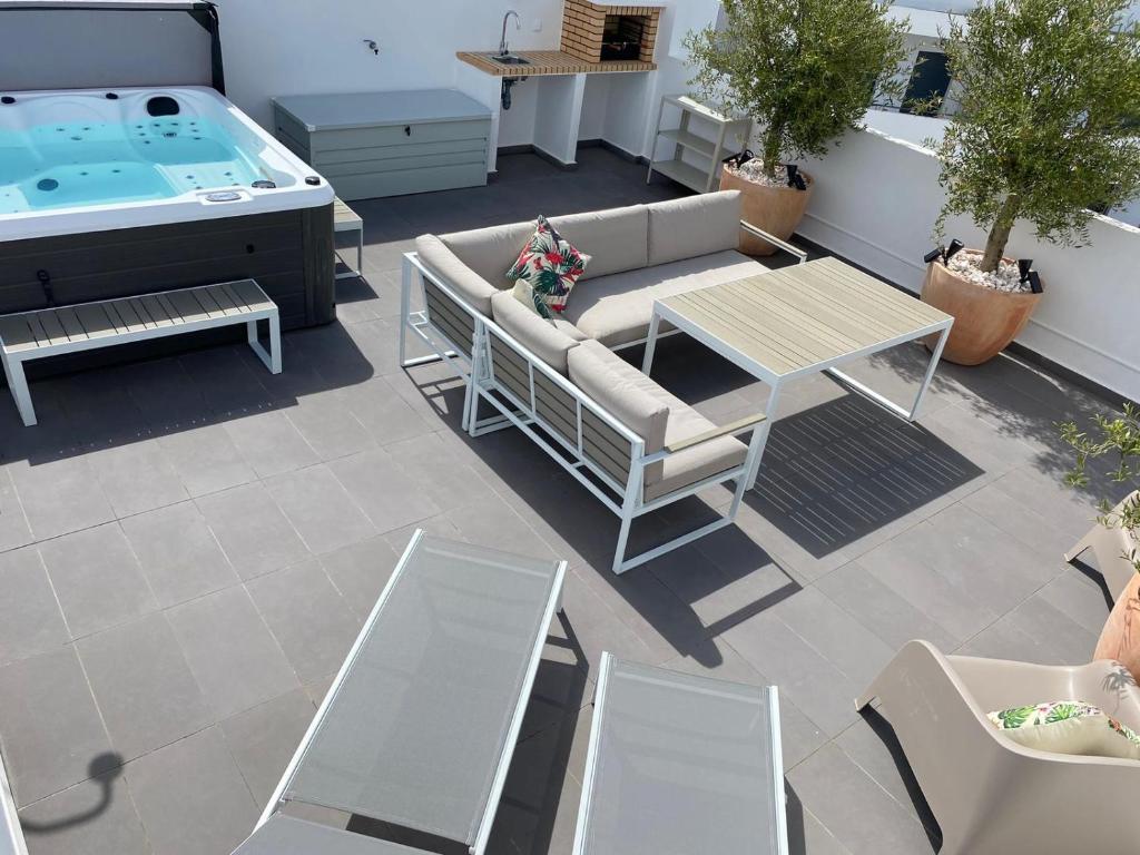 patio con divano, tavolo e vasca idromassaggio di Luxury Two Bedroom Apartment with Private Roof Terrace and Hot Tub ad Alvor