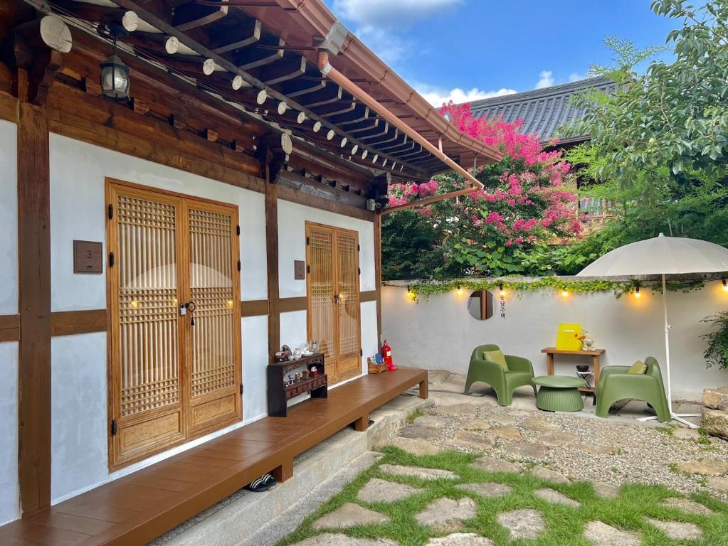 un patio con sillas, una mesa y una sombrilla en Pungnam House en Jeonju