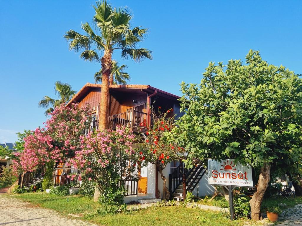 a resort with a palm tree and a sign at Sunset Boutique Hotel & Apartments in Cıralı