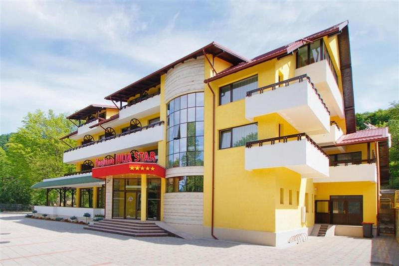 un grand bâtiment jaune avec un magasin dans l'établissement Pensiunea Iulia Star, à Băile Olăneşti