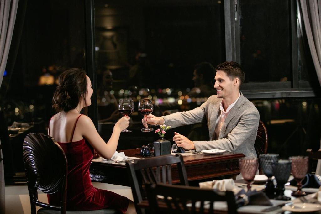 a man and woman sitting at a table drinking wine at Lucien Hanoi Lakeside Hotel & Rooftop in Hanoi