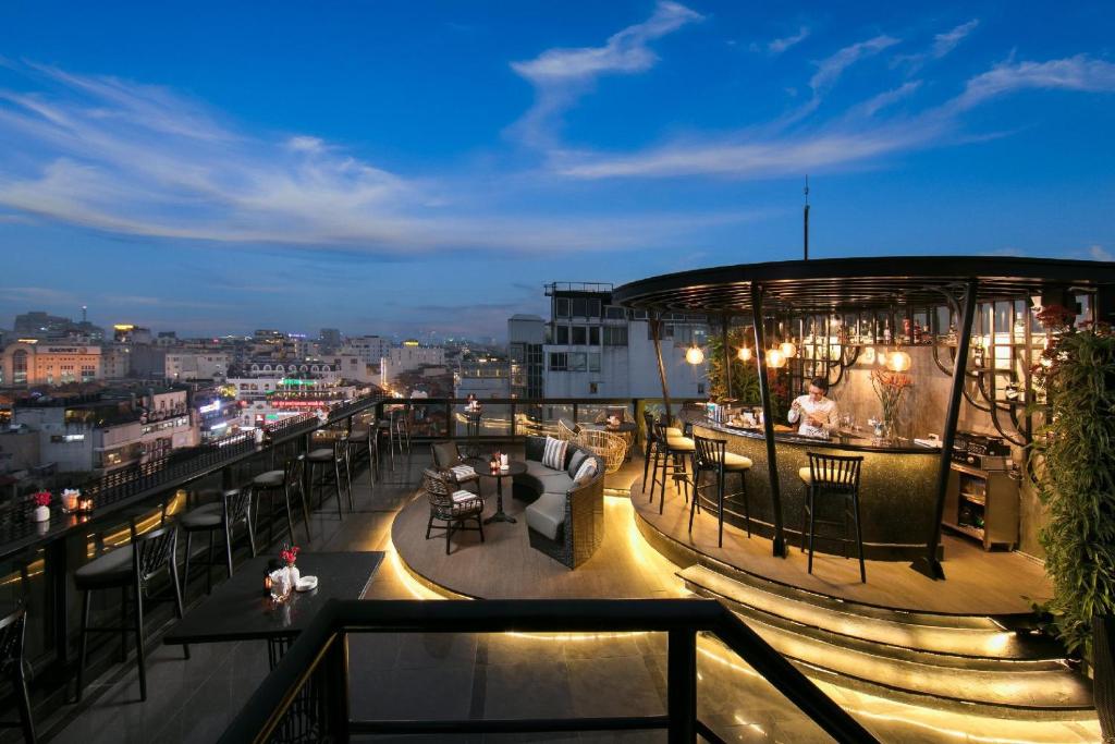 a rooftop bar with a view of a city at night at Lucien Hanoi Lakeside Hotel & Rooftop in Hanoi