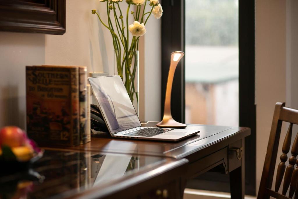 a laptop computer on a glass table with a vase of flowers at Lucien Hanoi Lakeside Hotel & Rooftop in Hanoi