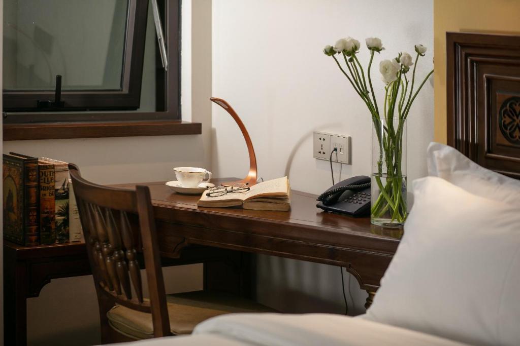a desk with a telephone and a vase of flowers at Lucien Hanoi Lakeside Hotel & Rooftop in Hanoi