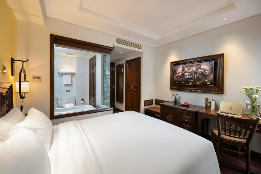 a bedroom with a bed and a desk and a television at Lucien Hanoi Lakeside Hotel & Rooftop in Hanoi