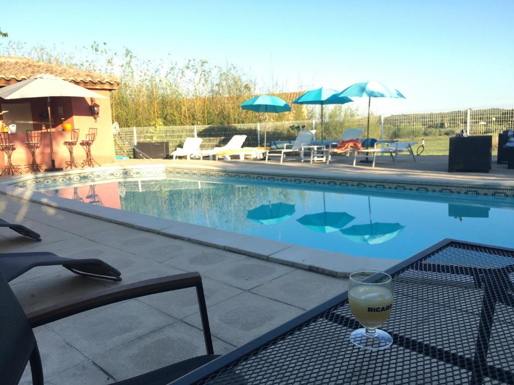 a glass of wine sitting on a table next to a swimming pool at Gites Còr Causy OLEANDER in Causses-et-Veyran