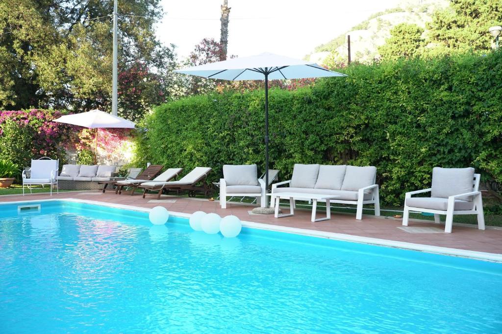 einen Pool mit Stühlen, einem Sonnenschirm und einem Pool in der Unterkunft Villa Losanna in Mondello