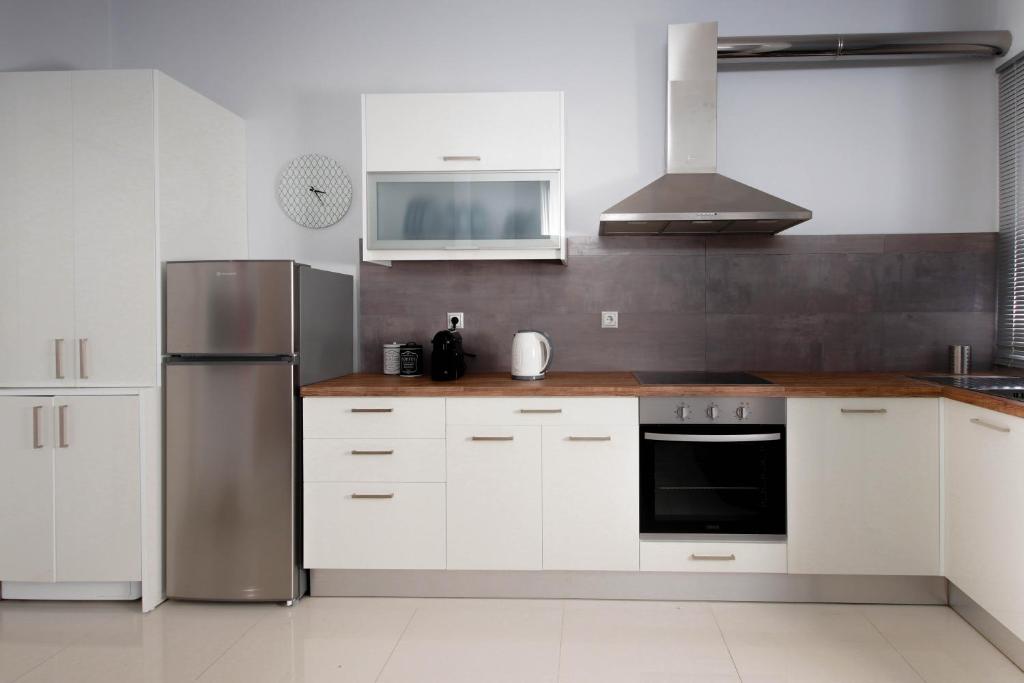 uma cozinha com armários brancos e um frigorífico de aço inoxidável em Twin Lofts Ταξιαρχών, a KalamataStay Property em Kalamata