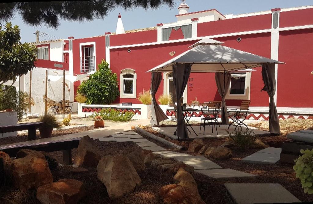 een rood gebouw met een tuinhuisje in een tuin bij Guest House Almeixar in Almancil