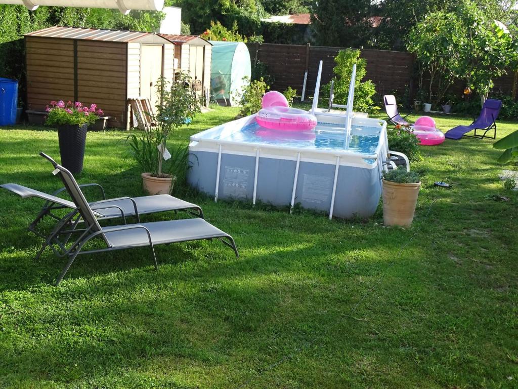 uma piscina num quintal com duas cadeiras e uma mesa em LA DATCHA em Saujon
